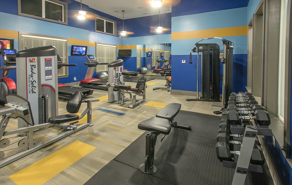 A gym with a variety of equipment including treadmills, weights, and exercise machines.